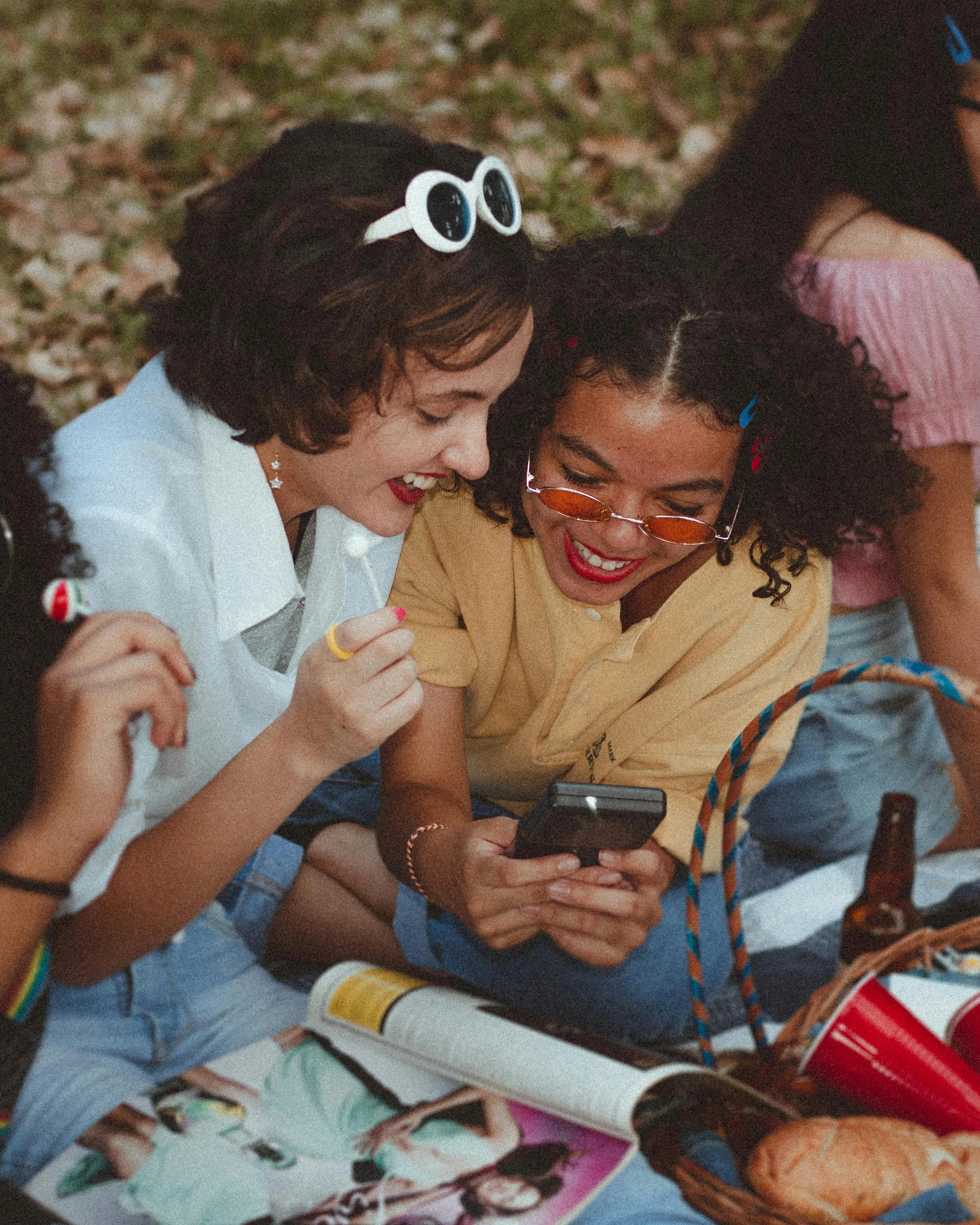 Duas amigas sorrindo enquanto olham o celular